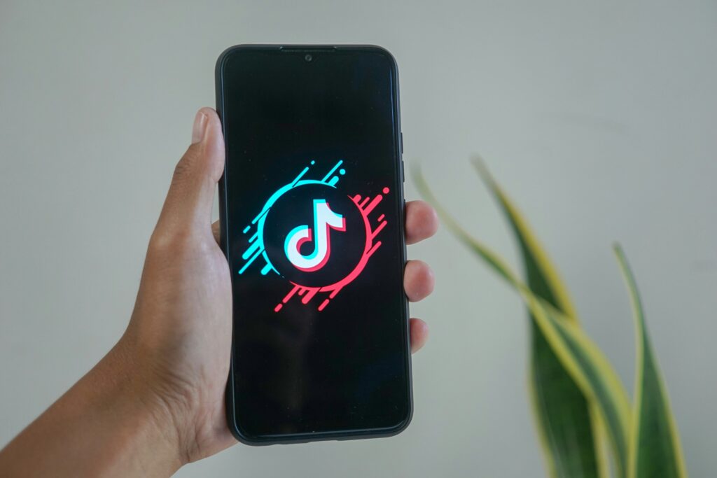 Person holding a phone with the TikTok logo on the screen.